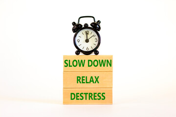 Destress symbol. Concept words Slow down Relax Destress on wooden block. Black alarm clock. Beautiful white table white background. Psychological business slow down Relax destress concept. Copy space.