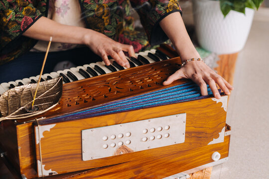 Hands of a woman sitting on the floor and playing the harmonium during the practice of kundalini yoga