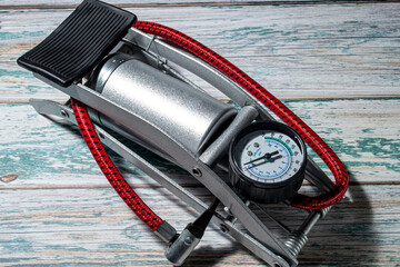 Silver foot pump for car and bicycle tires, on a green wooden background