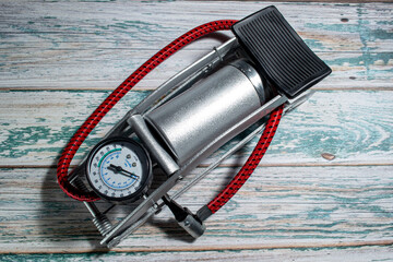 Silver foot pump for car and bicycle tires, on a green wooden background