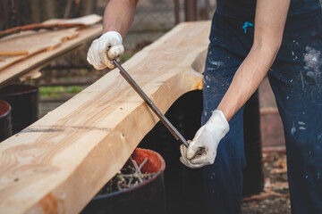 Handy woodcutter prepares larch wood for later processing. Planing wood. Working larch boards with traditional tools. Hand processing. Trimming the tree trunk. detail on the muscles that work