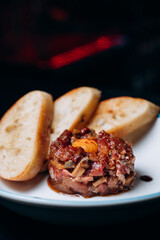 Beef steak tartare with raw egg yolk and croutons on a white plate. french cuisine. view from above