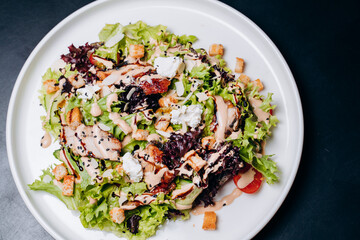 Caesar salad with chicken, Parmesan and wheat croutons on a vintage grey background. Light diet dinner.