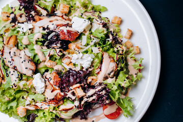 Caesar salad with chicken, Parmesan and wheat croutons on a vintage grey background. Light diet dinner.