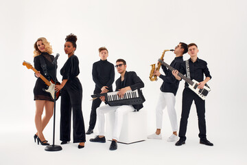 Portrait of diverse group of young people musical band playing with instruments - isolated on white background.