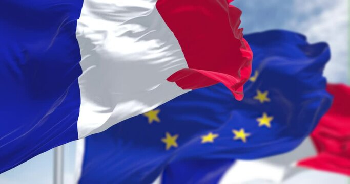 Detail of the national flag of France waving in the wind with blurred european union flag in the background on a clear day.