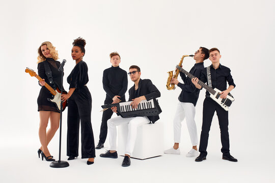 Portrait of diverse group of young people musical band playing with instruments - isolated on white background.