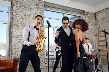 Repetition of multi ethnic jazz band in loft. Bass guitar player, electric guitar player, saxophonist and drummer at loft. Jazz music and jam session concept. passion for music and youth culture