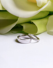 Stylish wedding rings made of white gold on a background of a bouquet of calla lilies. High quality...