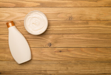 Shower gel and body cream on wooden background, top view