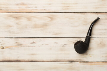 Smoking pipe on wooden background, top view
