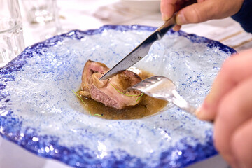Someone cutting a piece of beef rib on a plate, no faces are shown