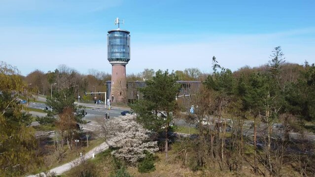 bird's eye view image rising between the trees with a view of a busy traffic road at the water tower of bussum in the Netherlands