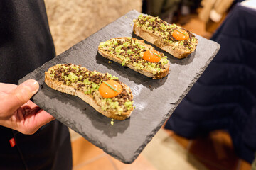 Tapenade of anchovies and couscous on toast on a black tray