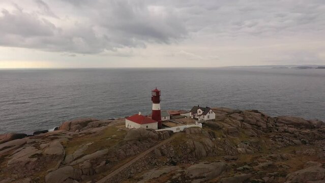 Ryvingen lighthouse at sunset - Red and white lighthouse on small island at southernmost point of Norway - Aerial with north sea and dramatic sky background