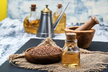 bowl of flax seeds and a bottle of fresh linseed oil on a linen cloth - obrazy, fototapety, plakaty