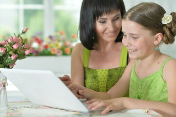 portrait of   mother and daughter using laptop
