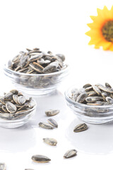 Three bowl of sunflower seeds with sunflower on white background. Vertical format.