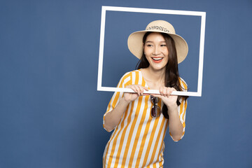 Young Asian woman tourist holding a picture frame isolated on blue background