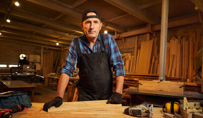 Portrait of Senior Professional carpenter in uniform working in the carpentry workshop