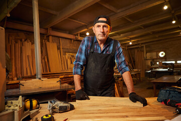Portrait of Senior Professional carpenter in uniform working in the carpentry workshop
