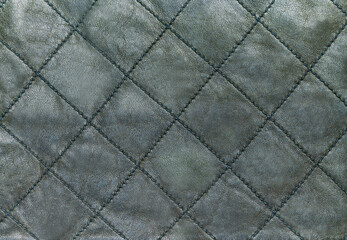 Fototapeta premium Green quilted genuine leather background, close up