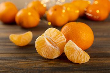 Tangerines whole and peeled on brown textured wood with lights background.Cetrus. Side view.