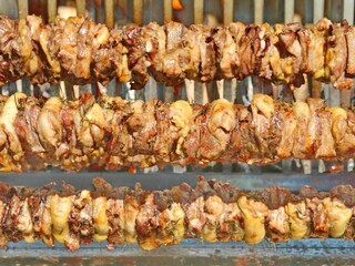 spit with chicken meat and pork in the rotisserie