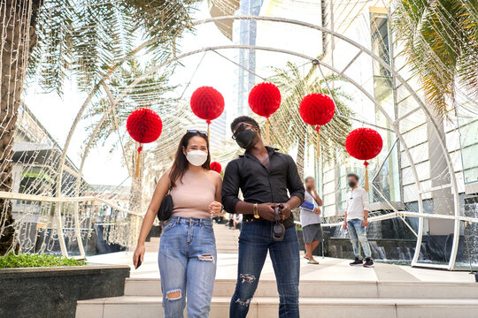 Two multiracial friends wearing facial mask walking in a shopping mall