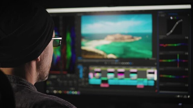 An experienced video production engineer works on a PC. A man is doing color grading for a video. Professional