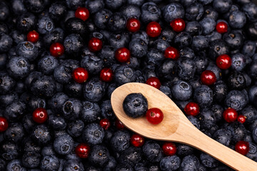 berries background. Ripe blueberry and red currant with wooden spoon top view image.