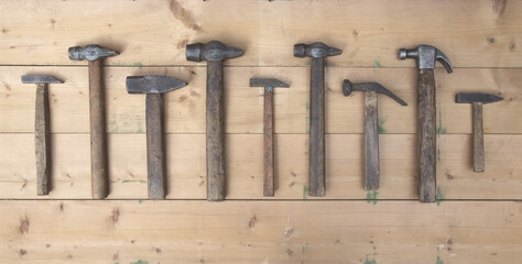 Many different hammers with a wooden handle on the background of light boards