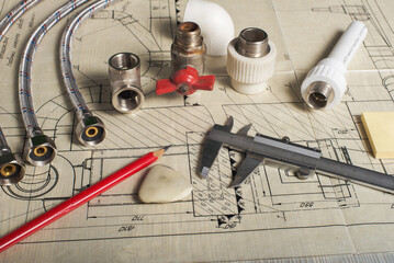 Drawing up a plumbing repair plan with spare parts and tools on blueprints.