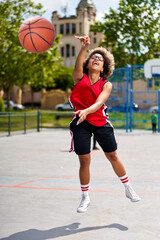 Basketball player performing slam dunk on a street court. Woman in sportswear playing streetball on...