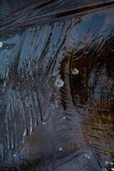 Freezing. Beautiful ice on a puddle with orange dry leaves, top view