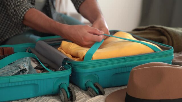 Traveler man is preparing for their travel adventure, packing clothes into bag, getting ready for road trip - travelling, happy concept. No face. 4k footage