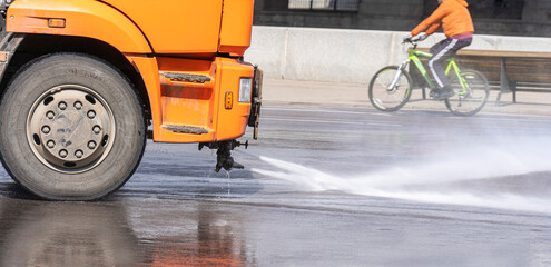Fototapeta na wymiar A watering machine washes a city street