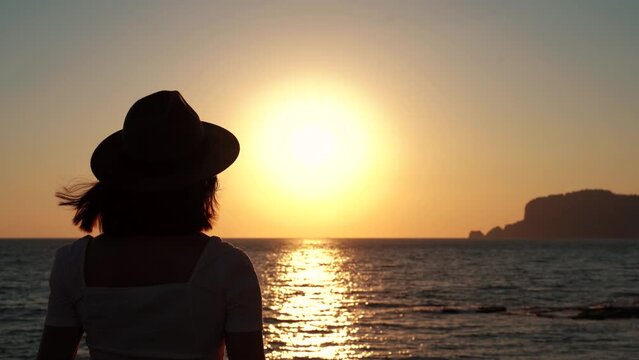 Silhouette of beautiful young woman photographing the sunset by the sea , on beach enjoying golden lights sky. summer vacation concept . 4k footage