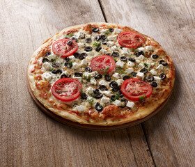 Pizza with cheese, olives and tomatoes on wood table