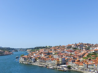 Fototapeta na wymiar Porto, Portugal. View from Porto to Vila Nova de Gaia. Douro river and ancient historic buildings. Sunny day, blue clear skies.
