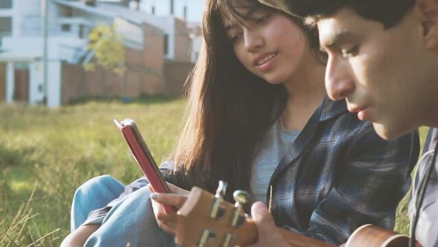 Mujer aprendiendo a tocar ukulele (Guitarra peque&ntilde;a) en un parque al atardecer.