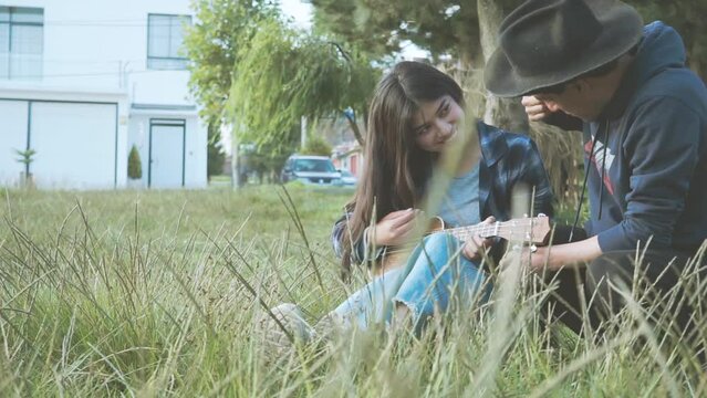 Mujer aprendiendo a tocar ukulele (Guitarra peque&ntilde;a) en un parque al atardecer.