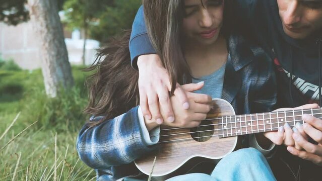 Mujer aprendiendo a tocar ukulele (Guitarra peque&ntilde;a) en un parque al atardecer.