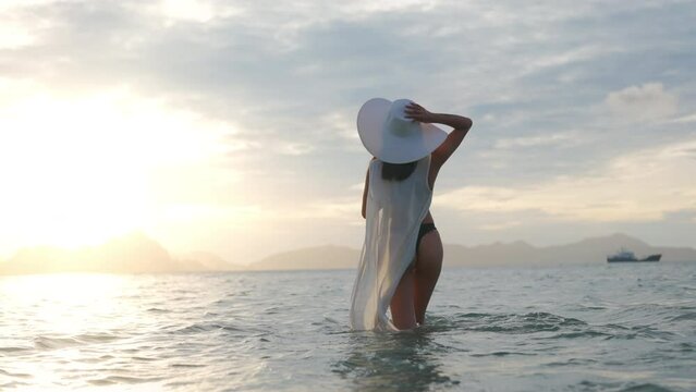 Woman In Thong And Sun Hat In Sea At Sunset