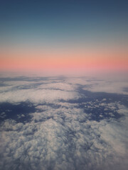 Sunset cloudscape, aerial view out of the plane window above the fluffy clouds. Tranquil sky evening scene, misty nebula. Air fresheners, celestial beauty, vertical background