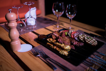 A plate of Chicken and beef BBQ with grilled tomatoes, potatoes and onions 