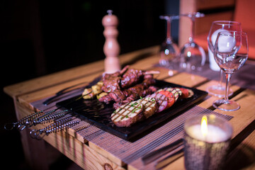 A plate of Chicken and beef BBQ with grilled tomatoes, potatoes and onions 
