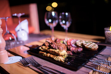 A plate of Chicken and beef BBQ with grilled tomatoes, potatoes and onions 