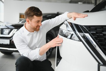 Man adult customer male buyer client chooses auto wants to buy new automobile touch check car in showroom vehicle salon dealership store motor show indoor. Sales concept