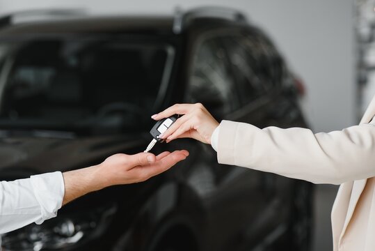 Businessman Exchange Handing Over The Car Keys For To A Young Women.